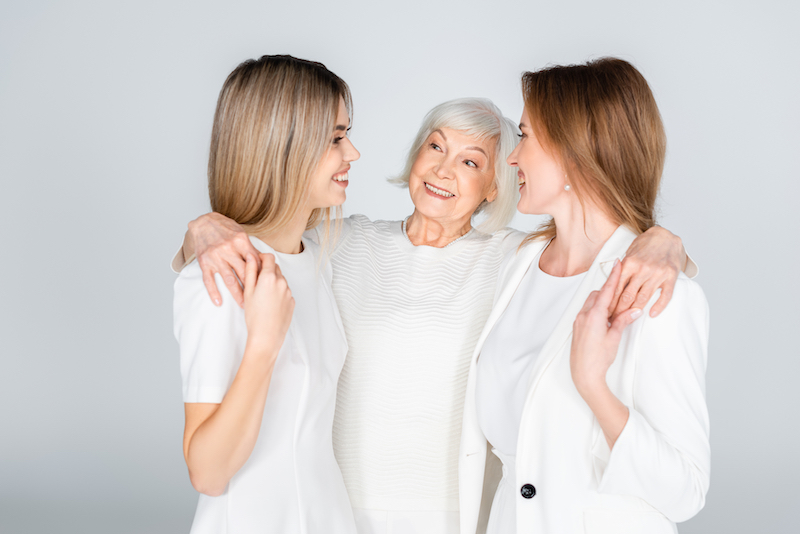 Three Generation Of Cheerful Women Smiling While Hugging Isolated On Grey